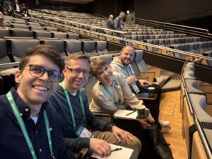 Conticas AI Center of Excellence på GAIA 2026 – Håkan Åkerblom, Amanda Orrbeck, Sebastian Wesselhoff och Björn Larsson tittar in i kameran från publiken under en av sessionerna